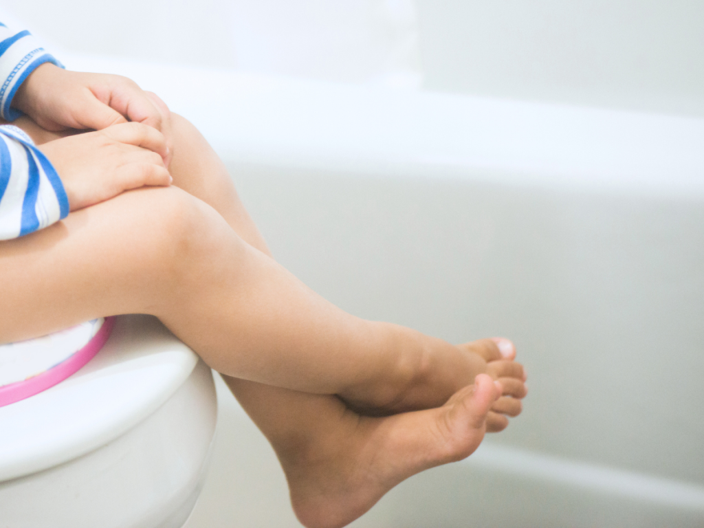 Child with autism spectrum disorder (ASD) sitting on toilet.